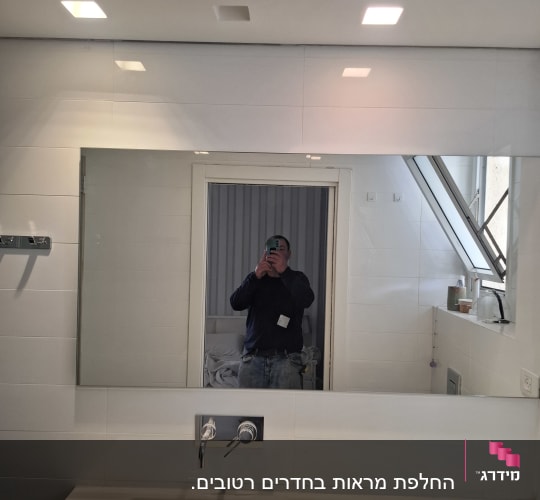 מראה מלבנית רחבה מותקנת מעל כיור בחדר רחצה